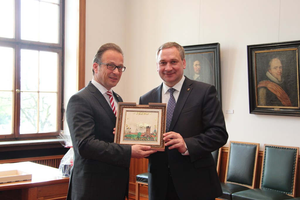 Der Stadtpräsident von Pskow, Ivan Zezerski (r.), überreicht Bürgermeister Reiner Breuer eine Uhr, auf der Motive aus Neuss und Pskow verbunden sind.