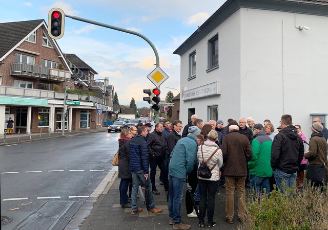 Eine größere Gruppe Menschen versammelt sich an einer Kreuzung.